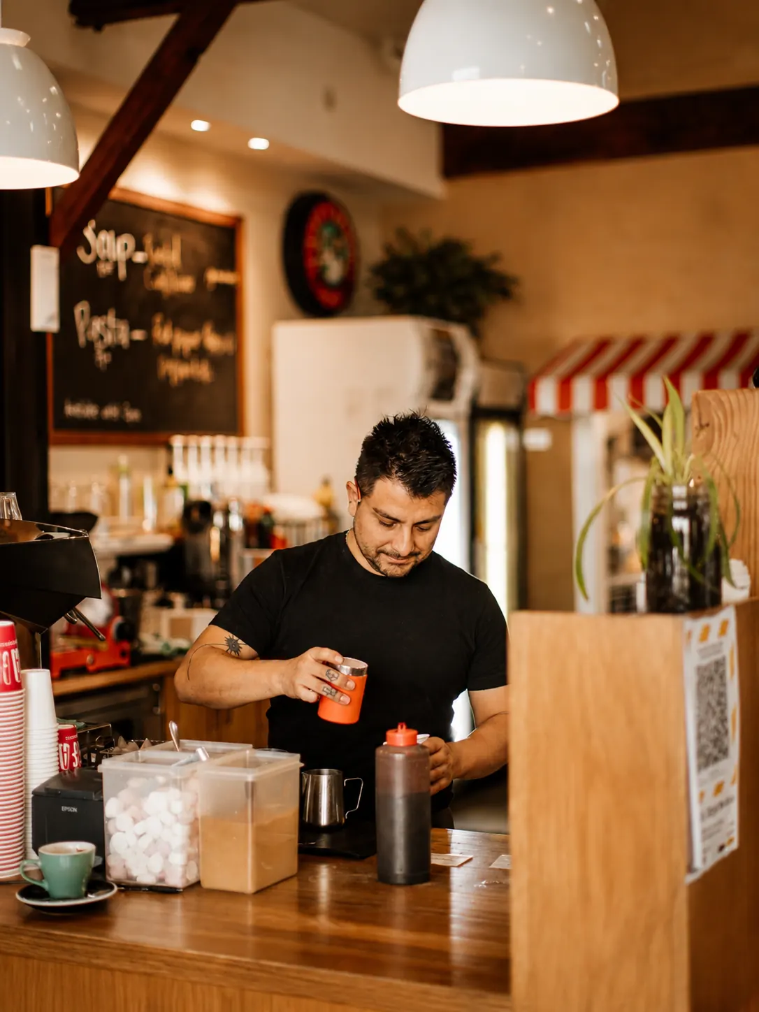 A team member preparing a drink behind the counter at Mitchelli's Cafe Rinato